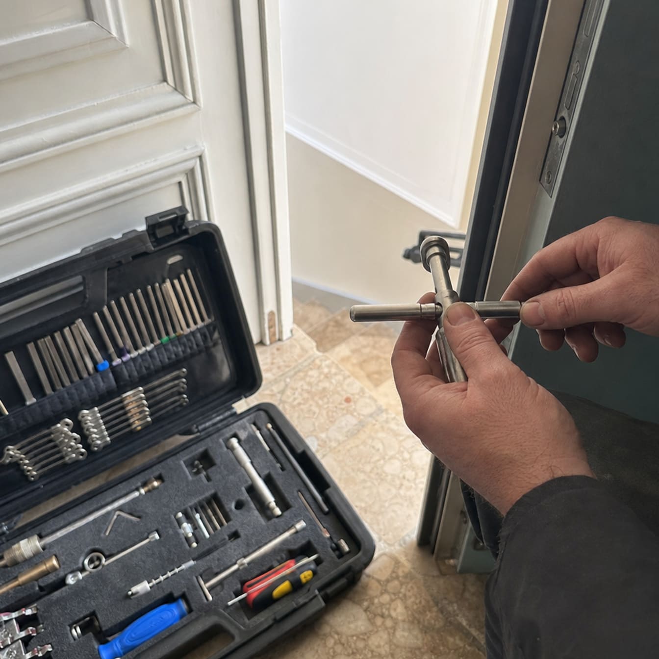valise outillage serrurier ouverte sur palier avec outils